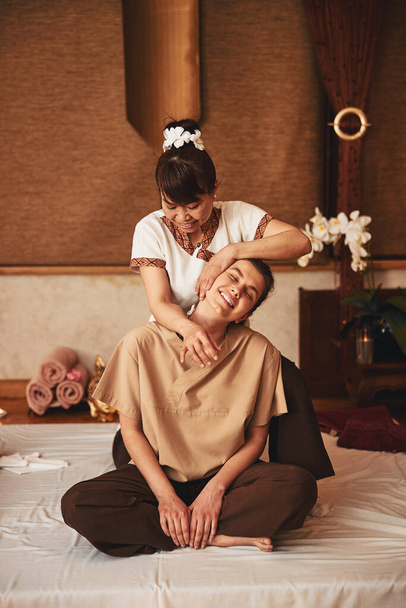 Massaggiatrice qualificata appoggiata testa di donna felice a sinistra - Foto, immagini