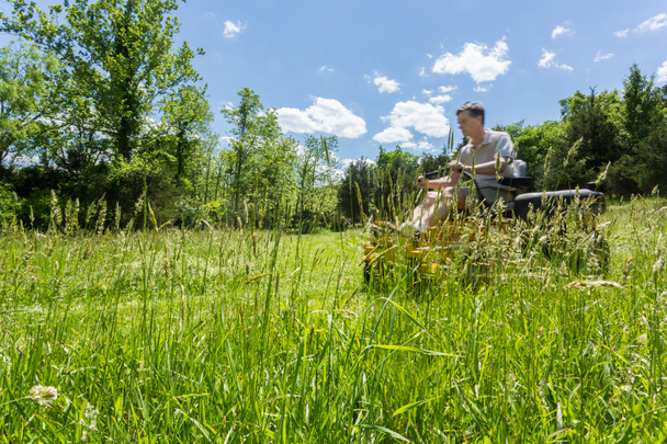 ゼロのシニア男性草原に芝刈り機を回す - 写真・画像