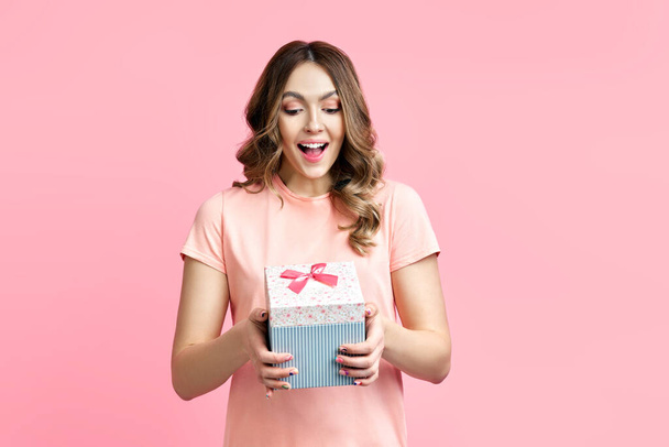 Excited smiling woman woman holding gift box over pink background - Fotografie, Obrázek