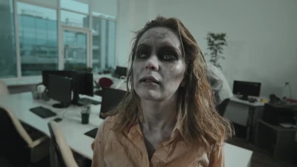 zbliżenie się bezmyślne kobieta zombie z soczewki kontaktowe i straszne SFX makijaż patrząc w aparat fotograficzny w biurze - Materiał filmowy, wideo