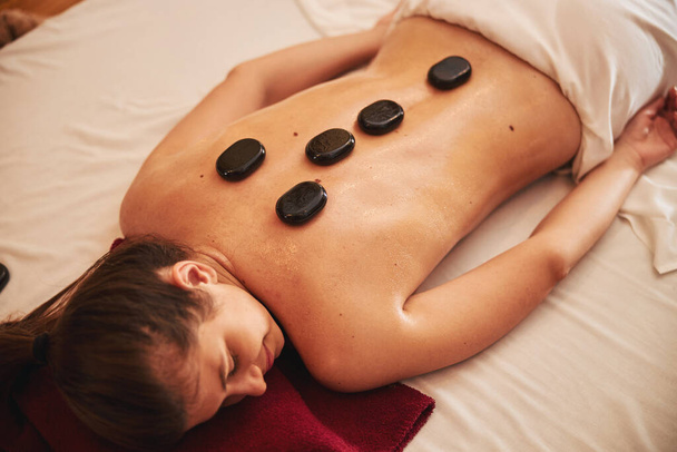 Pierres de massage sur la colonne vertébrale et le haut du dos du client spa - Photo, image