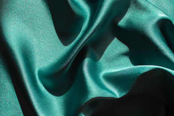 Green satin fabric pleats close-up. Abstract trend background of the 2021 Tidewater Green color.Luxury elegant bright texture with hard light with copyspace.Banner design for Christmas,Valentine's day - Photo, Image