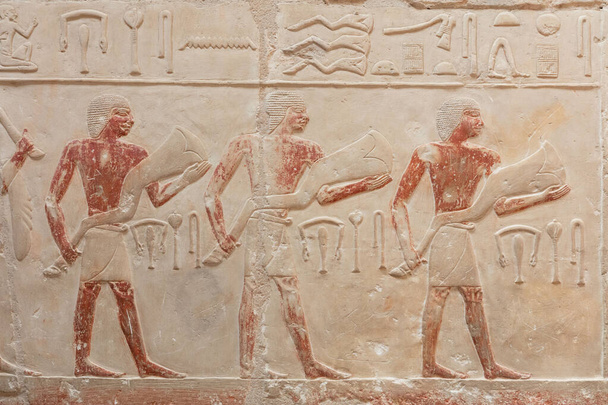 Salaperäinen egyptiläinen kaiverrettu lukuja valon seinään. - Valokuva, kuva