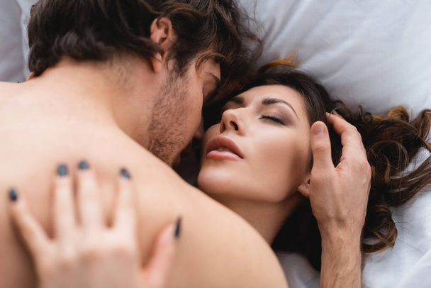 Young man touching sensual woman on bed  - Fotó, kép