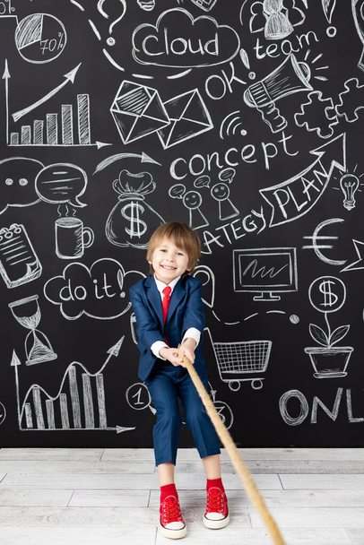 Bright idea! Funny child student in class against black chalkboard. Happy kid pretend to be businessman. Online education and e-learning concept. Back to school - 写真・画像