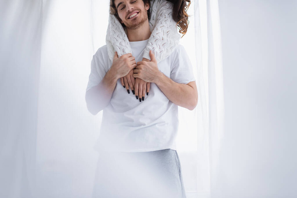 Woman embracing boyfriend near curtain at home  - Zdjęcie, obraz