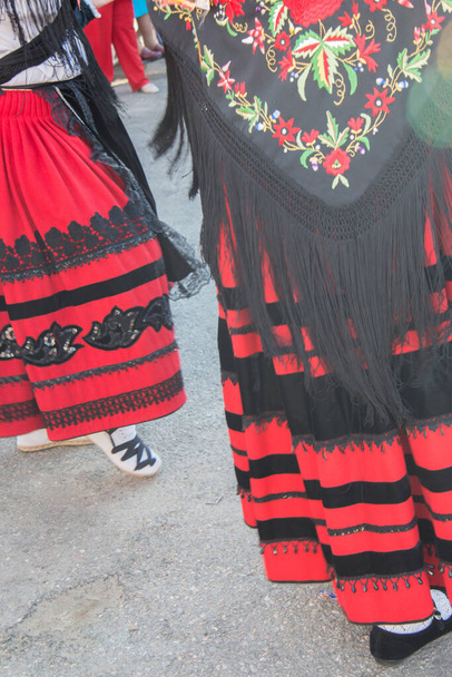 女性はセゴビアの伝統的な衣装で路上で踊ります。赤いスカートと刺繍  - 写真・画像