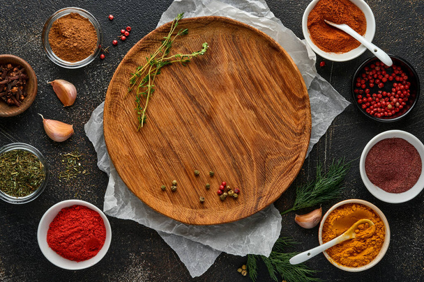 Set of Indian fragrant spices and herbs on a black stone background. Turmeric, dill, paprika, cinnamon, saffron, basil and rosemary in a spoon. Top view. Mock up. - Фото, зображення