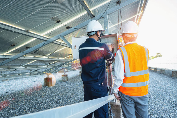 İşçiler, normal akımı doğrulamak için güneş enerjisinden üretilen elektrik kablolarının akımını ölçmek için klemp metre kullanırlar. - Fotoğraf, Görsel