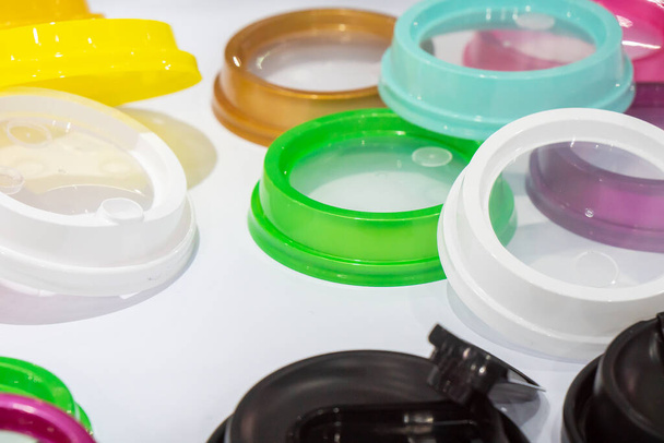 The pile of multi-colors plastic  drinking cup lid from injection processing. The plastic injection part manufacturing concept.  - Foto, immagini