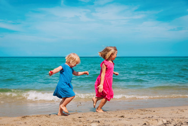 χαρούμενα χαριτωμένα κοριτσάκια τρέχουν και παίζουν στην παραλία - Φωτογραφία, εικόνα