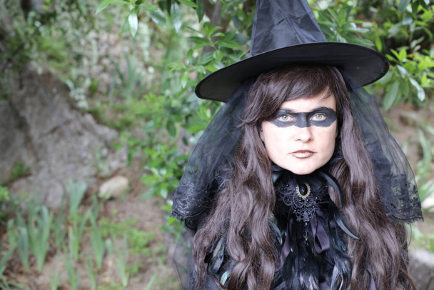 portré fiatal nő fekete ruhában festék a szemét a szabadban a parkban, boszorkány koncepció - Fotó, kép