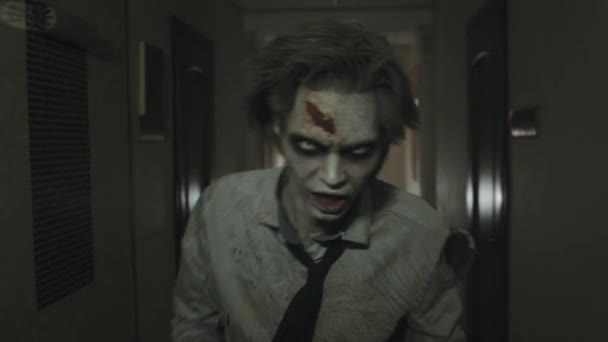 Plan de suivi de l'homme zombie effrayant avec maquillage SFX et lentilles de contact courant le long du couloir sombre et de la caméra suivante - Séquence, vidéo