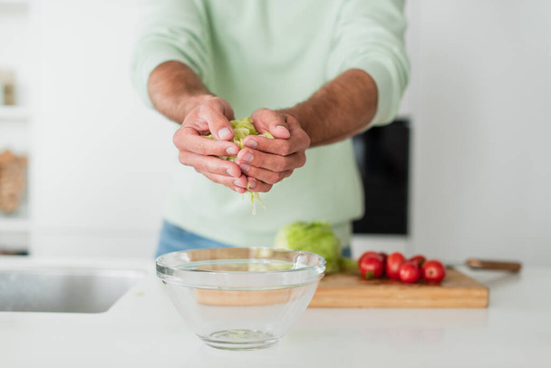 cropped view of blurred man preparing fresh vegetable salad in kitchen - Foto, Imagem