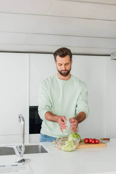man preparing salad from fresh vegetables for breakfast - Foto, Bild