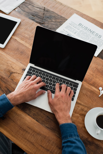 visão parcial do freelancer digitando no laptop perto de jornal e xícara de café - Foto, Imagem