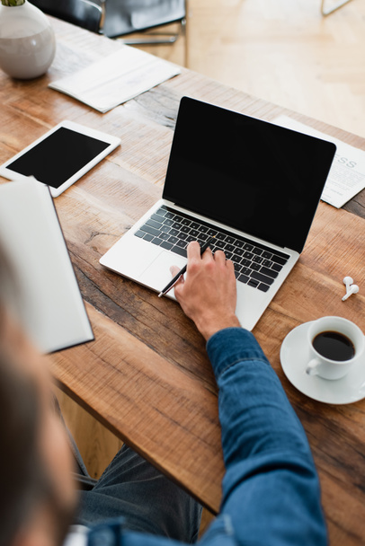 visão parcial do freelancer trabalhando no laptop perto de tablet digital e xícara de café - Foto, Imagem
