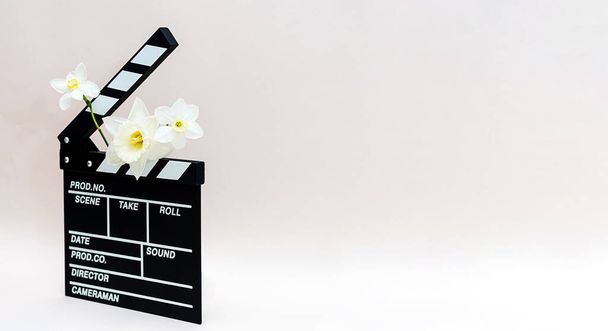 Tablero de película con flores de primavera. Bodegón mínimo de tablón de aplausos para hacer flores de cine de vídeo y narcisos. - Foto, Imagen