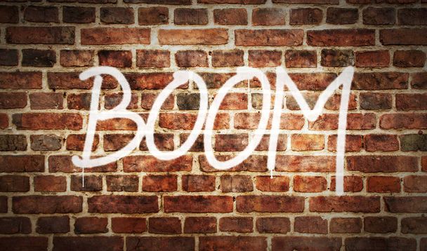 Boom spray painted inscription on the brick wall. Urban abstract artwork. Graffiti art concept of comic style right now. Airbrush paint with text template in hand. - Photo, Image