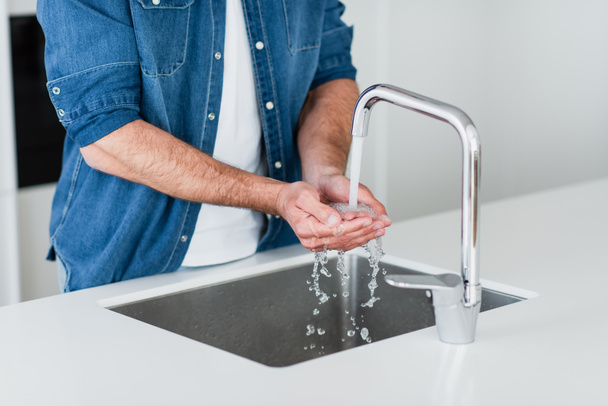 家で手を洗うデニムシャツの男の部分的な眺め - 写真・画像