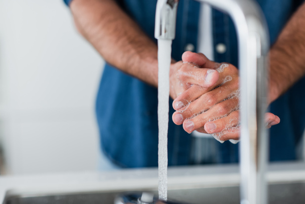 cropped view of blurred man washing hands with soap - 写真・画像