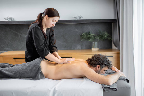 Жіночий масажист робить масаж чоловічому клієнту
. - Фото, зображення