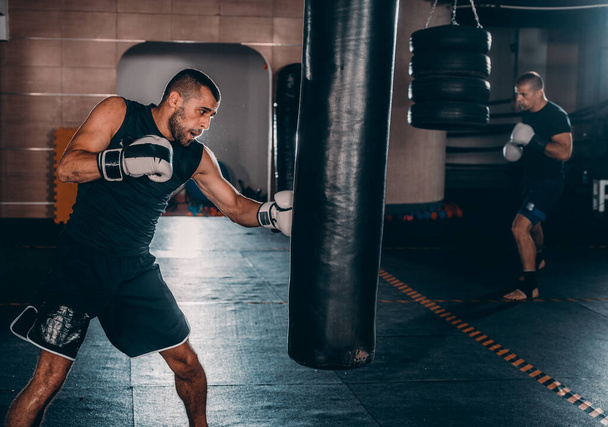 action d'un boxeur d'arts martiaux entraînement sur un sac de boxe dans la salle de gym
 - Photo, image