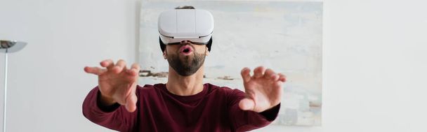 amazed man gesturing in vr headset while gaming at home, banner - Фото, изображение