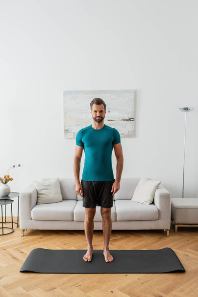 sportive barefoot man looking at camera while standing in mountain pose at home - Fotoğraf, Görsel