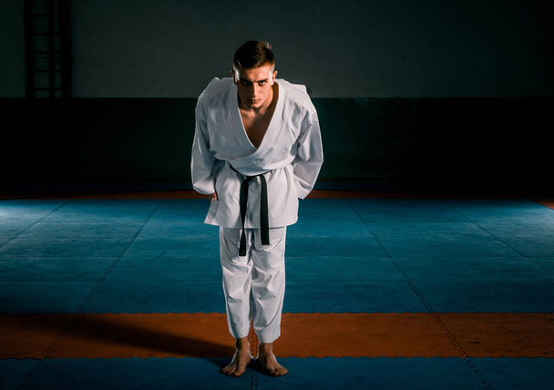 Karate-Mann mit schwarzem Gürtel posiert, Weltmeister auf schwarzem Hintergrund - Foto, Bild