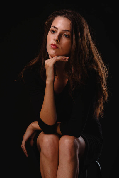 Ritratto di una giovane donna vestita con gonna corta e tacchi alti neri seduta sul loro - Foto, immagini