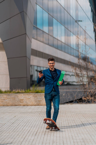 Full length portrait of a businessman smiling and riding a skateboard - Photo, Image