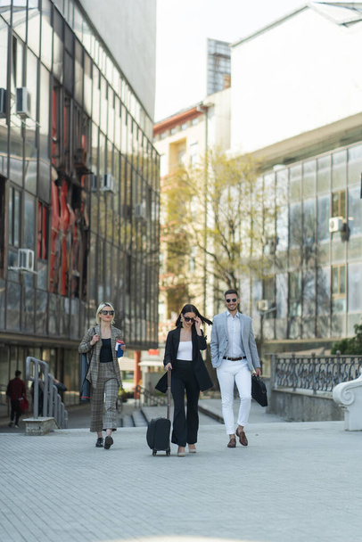 Três pessoas de negócios vestidos casuais estão sorrindo enquanto caminham juntos em direção à empresa - Foto, Imagem