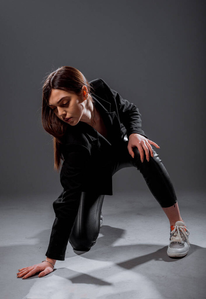 Body shot of a stylish woman posing in black trendy jacket and leather pants - Fotó, kép