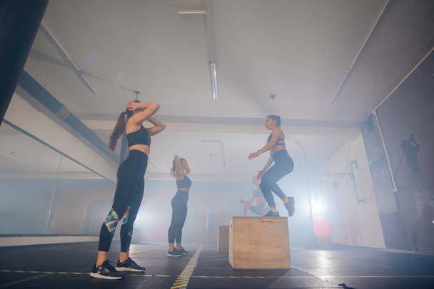 Молодые атлетичные девушки растягиваются на ступеньках и готовятся к фитнес-тренировкам - Фото, изображение