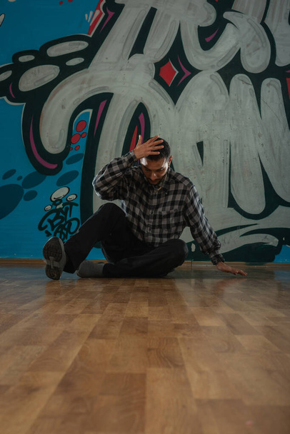 Trendy young man dancer dancing in front of graffiti. - Zdjęcie, obraz