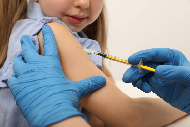 Doctor giving injection to little girl in hospital, closeup. Immunization concept - 写真・画像