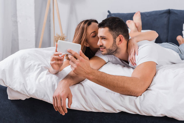 Barbudo homem tomando selfie perto namorada na cama  - Foto, Imagem