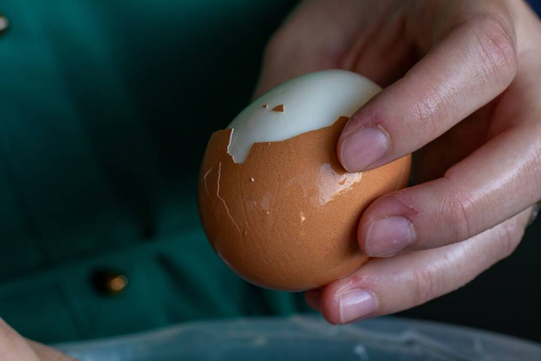 半熟のゆで卵を持っている人の手の肖像画は、それが冷たい料理で朝食、昼食、または多分夕食のために食べる準備をするためにさらにそれを剥離. - 写真・画像