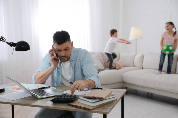Overwhelmed man combining parenting and work at home - Φωτογραφία, εικόνα