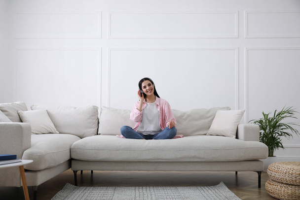 Woman with headphones on sofa in living room - Foto, Imagen