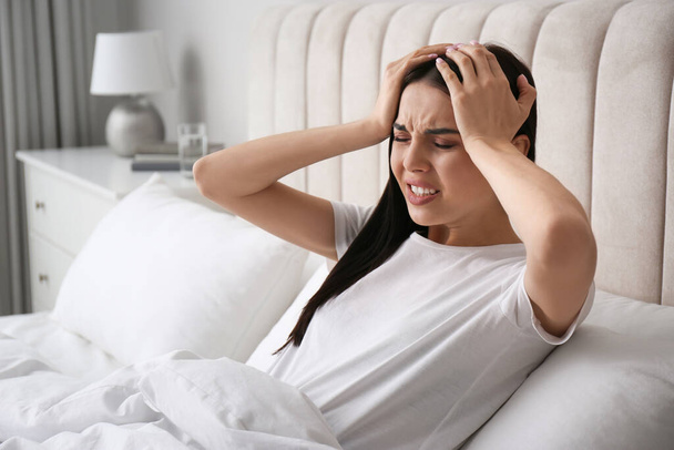 Young woman suffering from migraine in bed at home - Φωτογραφία, εικόνα