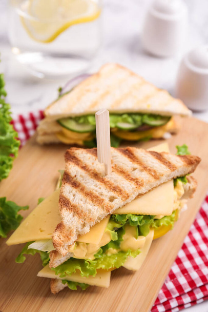 Wooden board with tasty cheese sandwich on table - Zdjęcie, obraz