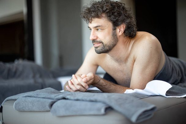 Bello uomo sdraiato in un salone spa in attesa di massaggio alla schiena - Foto, immagini