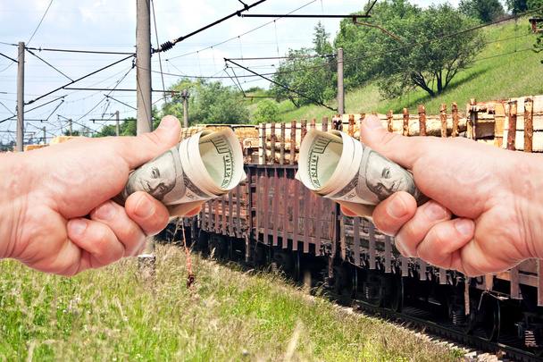 Mãos de homem com dólares americanos contra o comboio
 - Foto, Imagem