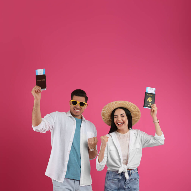 Paar toeristen met tickets en paspoorten op roze achtergrond - Foto, afbeelding