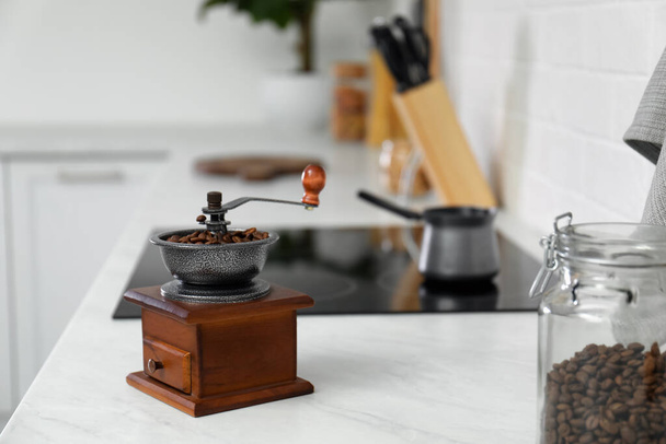 Vintage coffee grinder and beans on countertop in kitchen - Fotó, kép