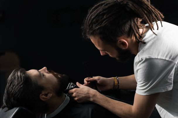 Trimming the beard with a shaving machine. Advertising for barbershop and men's beauty salon. - Photo, Image