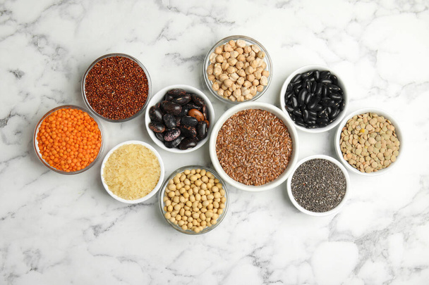 Different grains and seeds on white marble table, flat lay. Veggie diet - Foto, Bild