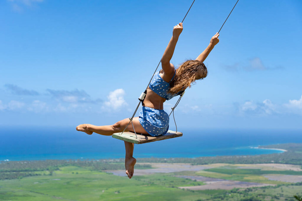 Young beautiful caucasian woman on the rope swing with sea and sky background. Concept of dream and happiness  - Foto, Imagem